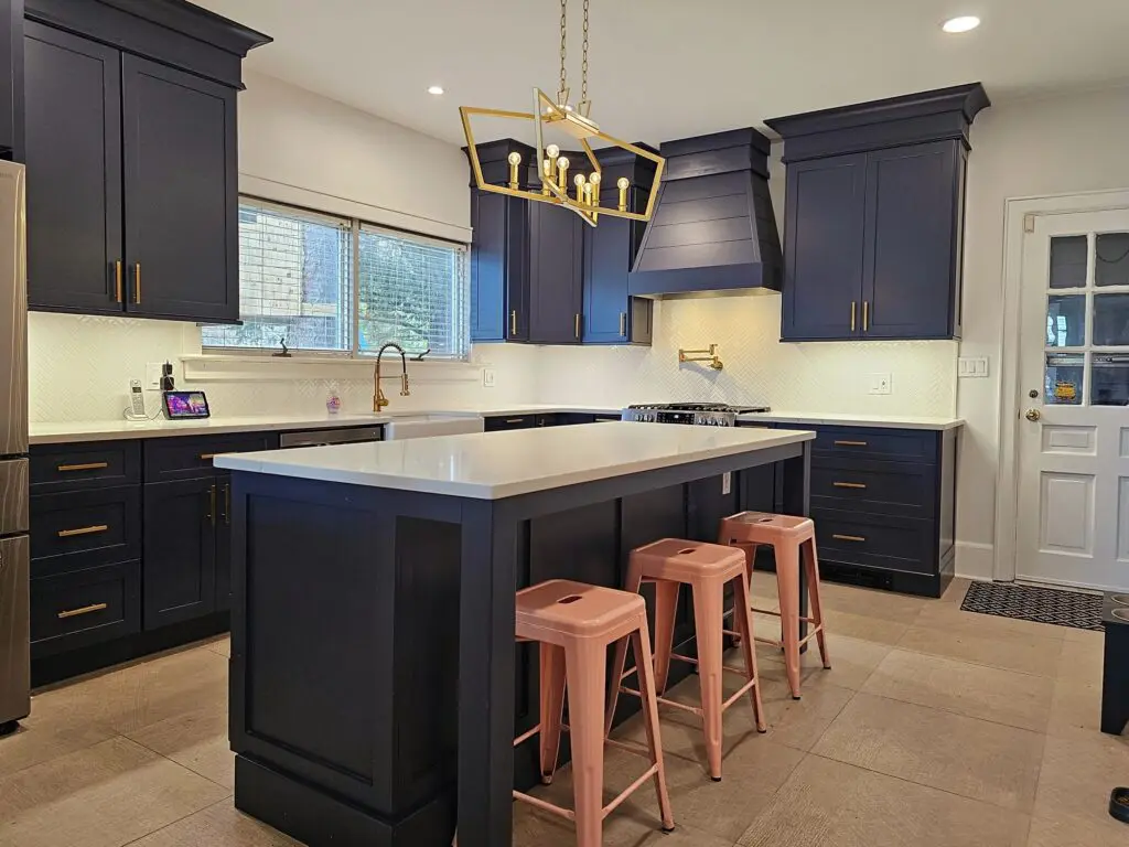 A kitchen with blue cabinets and pink stools.