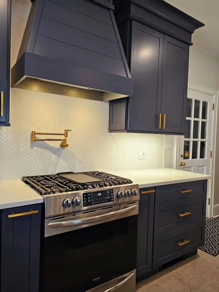 A kitchen with blue cabinets and gold hardware.