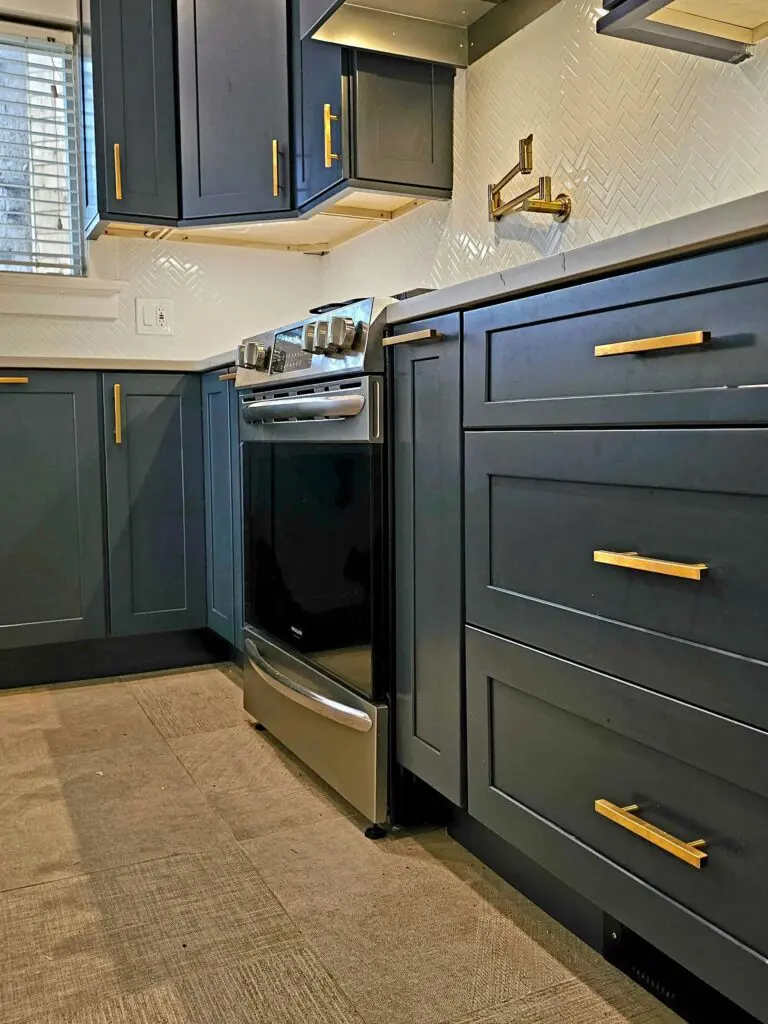 A kitchen with blue cabinets and gold hardware.