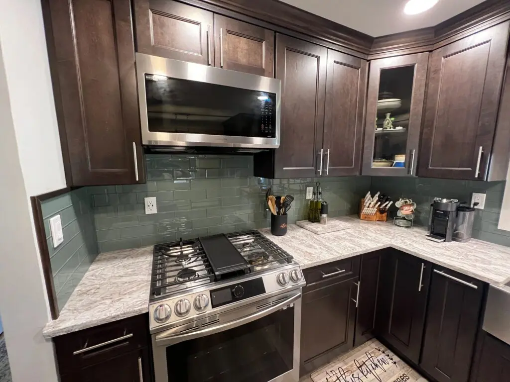 A kitchen with dark wood cabinets and white counter tops.