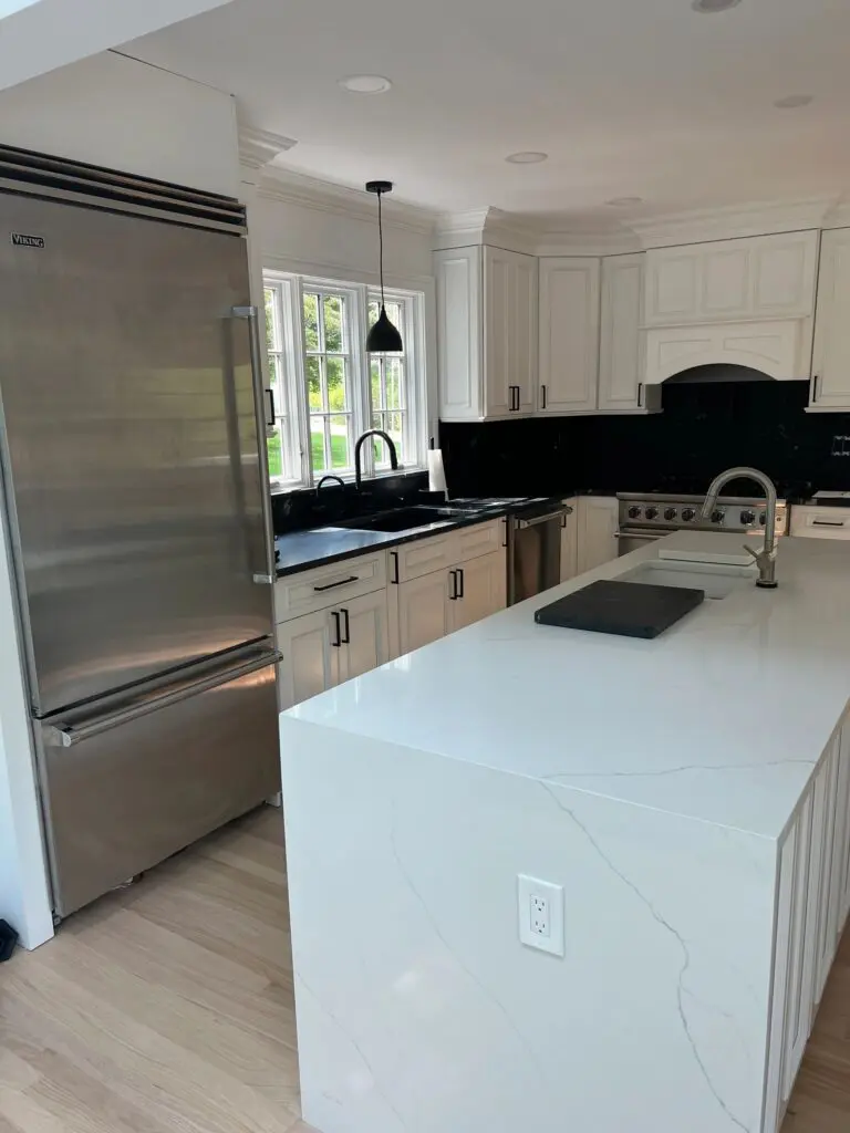 A kitchen with white cabinets and black appliances.