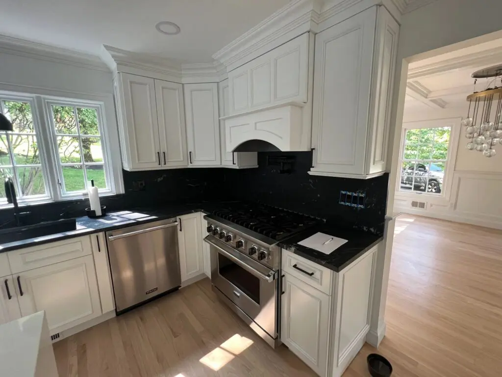 A kitchen with white cabinets and black counter tops.