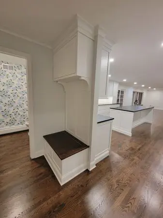 A room with wooden floors and white cabinets.