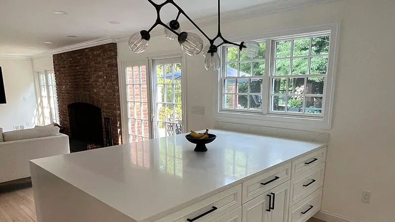 A kitchen with white cabinets and black handles.