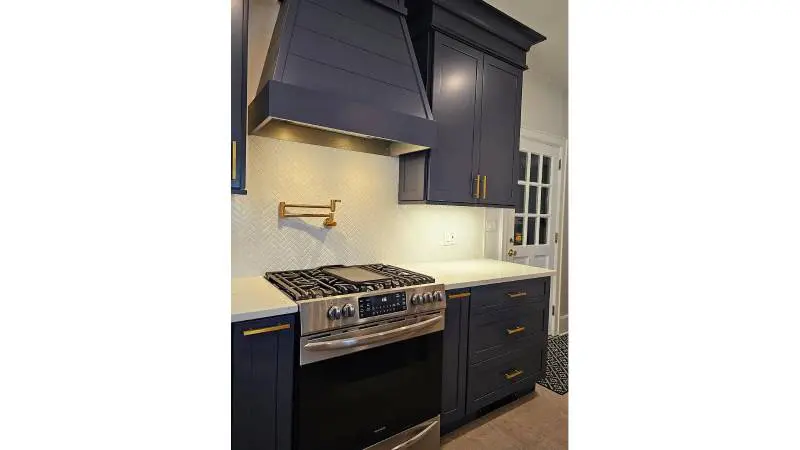 A kitchen with blue cabinets and black appliances.