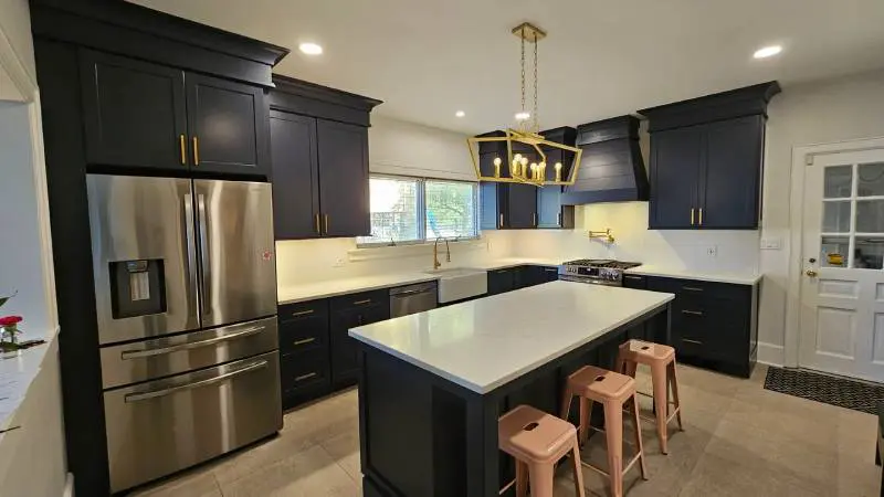 A kitchen with black cabinets and white counter tops.