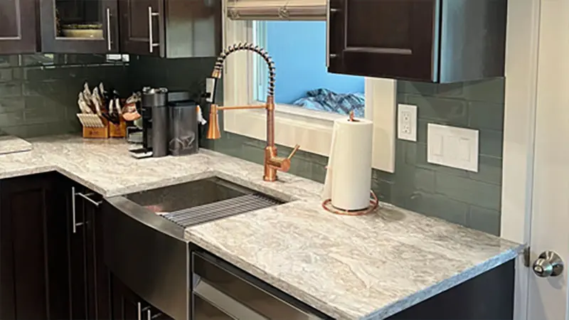 A kitchen with marble counter tops and stainless steel appliances.